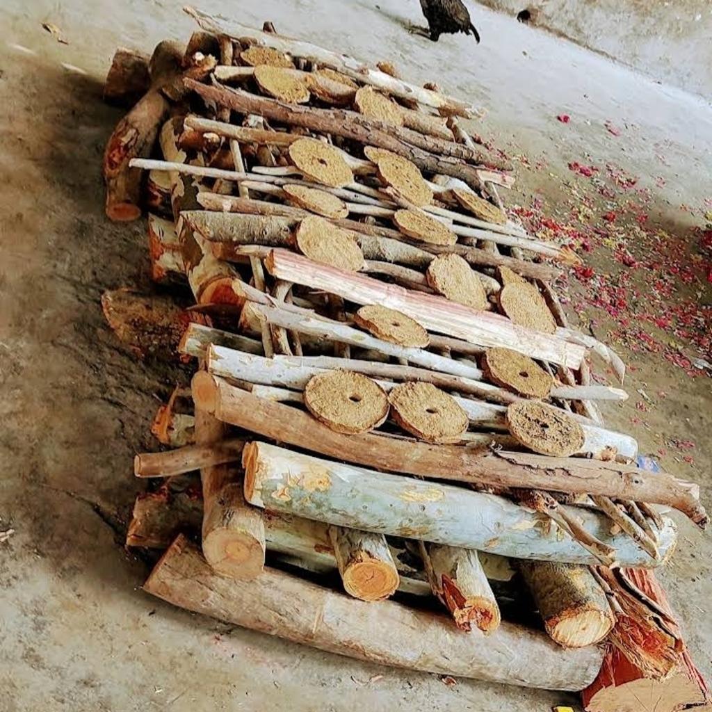 Wood cremation setup with logs and ritual materials at Bangalore cremation ground