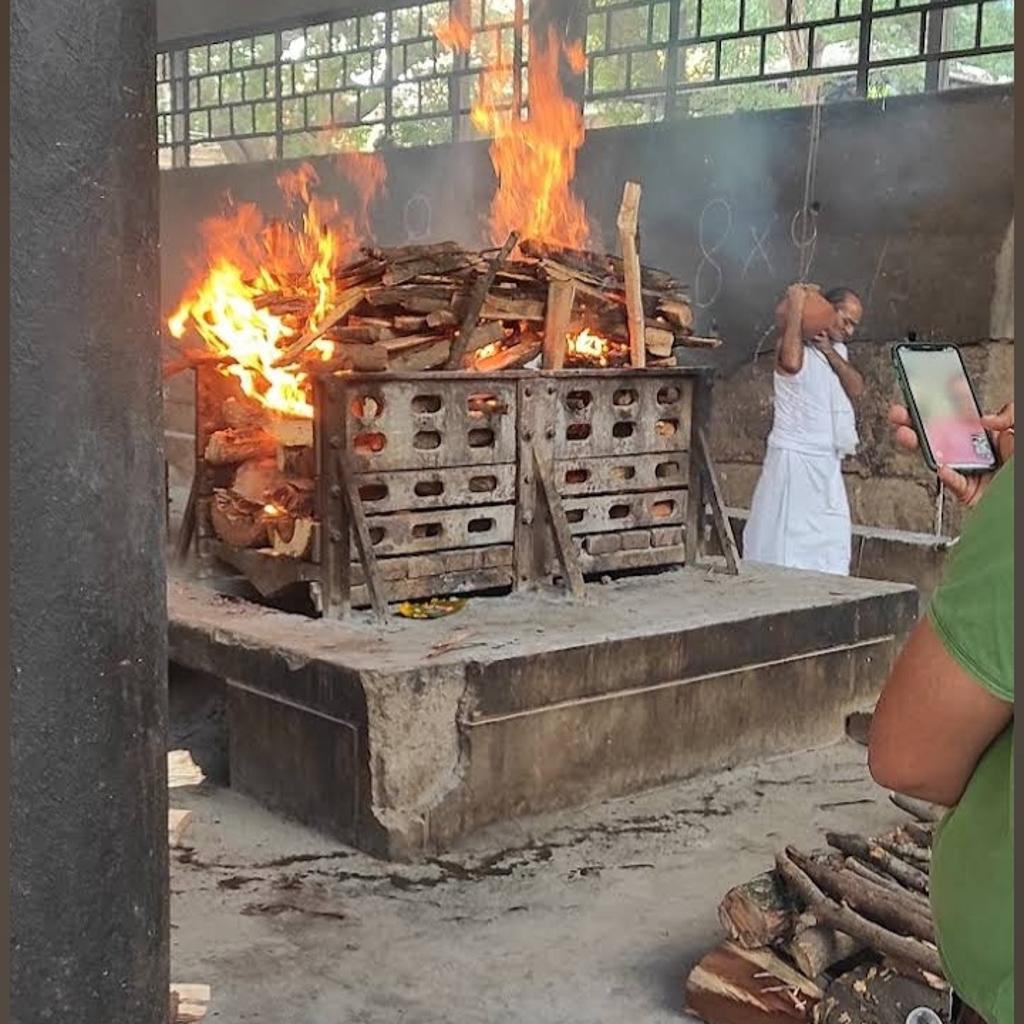 Active wood cremation process with burning pyre and priest performing last rites in Bangalore